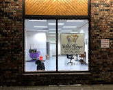 Storefront with large glass window displaying interior, surrounded by brick wall.